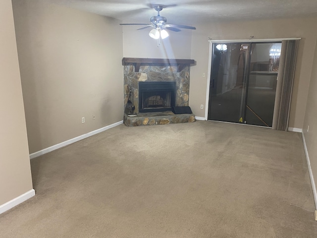 unfurnished living room featuring carpet, ceiling fan, and a stone fireplace