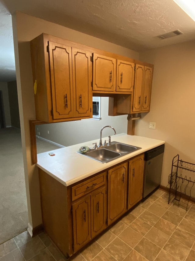 kitchen featuring a textured ceiling, stainless steel dishwasher, and sink