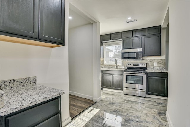 kitchen featuring backsplash, light stone counters, and appliances with stainless steel finishes