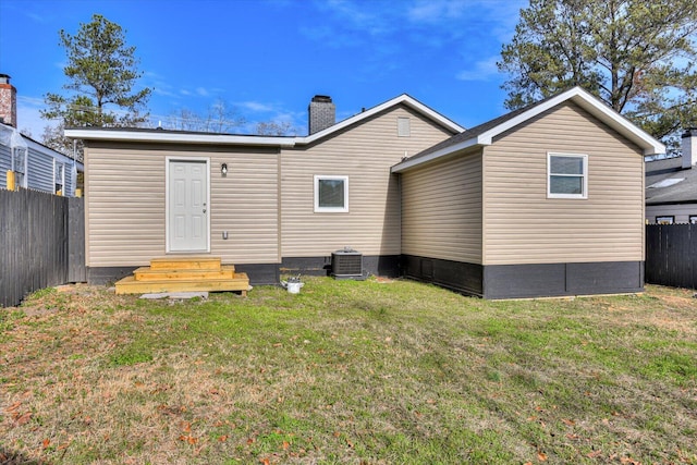 rear view of property featuring central air condition unit and a lawn