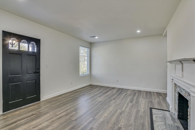 unfurnished living room with hardwood / wood-style flooring and a stone fireplace