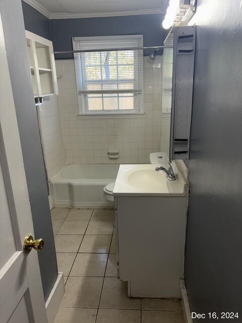 full bathroom with tiled shower / bath combo, tile patterned floors, toilet, vanity, and ornamental molding