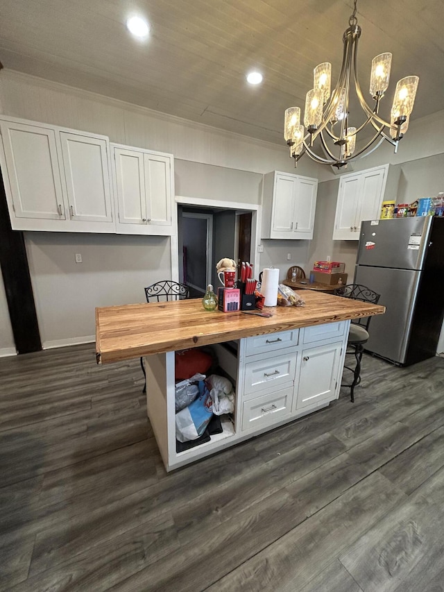 kitchen featuring dark wood-style flooring, hanging light fixtures, freestanding refrigerator, white cabinets, and wood counters