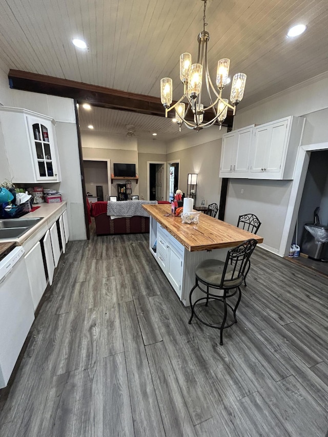 kitchen featuring wooden counters, hanging light fixtures, white cabinets, a sink, and dishwasher