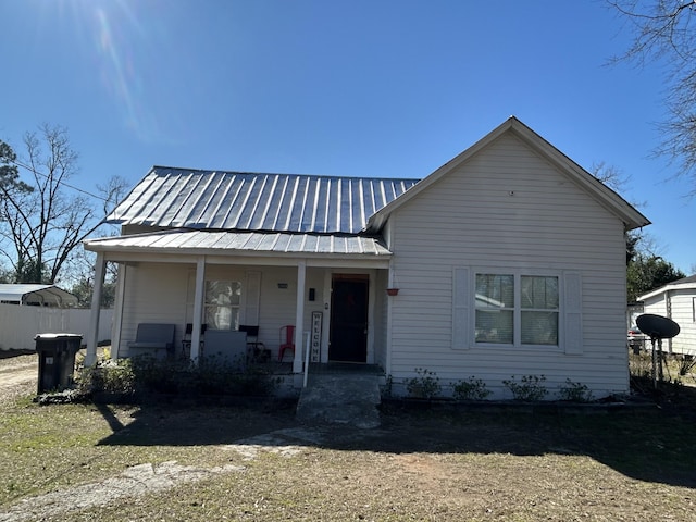 view of front facade with covered porch, metal roof, and fence