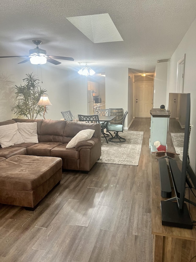 living room with a skylight, ceiling fan, wood-type flooring, and a textured ceiling