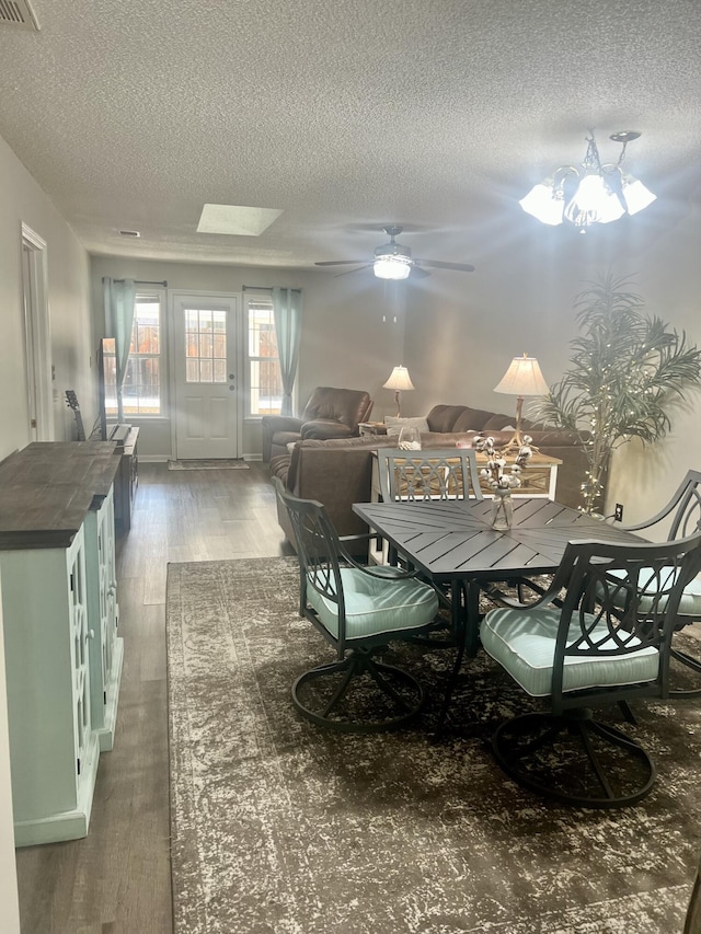 dining area with ceiling fan with notable chandelier, wood-type flooring, and a textured ceiling