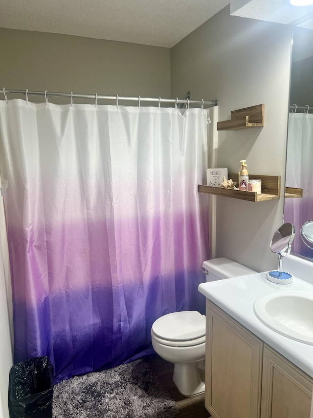 bathroom with a shower with curtain, vanity, a textured ceiling, and toilet