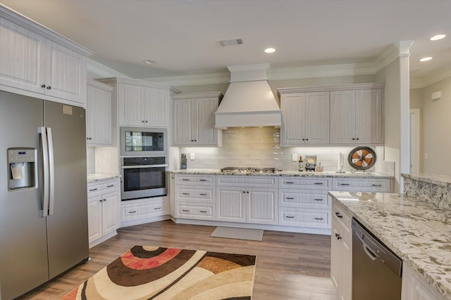 kitchen with stainless steel appliances, white cabinets, visible vents, and custom exhaust hood