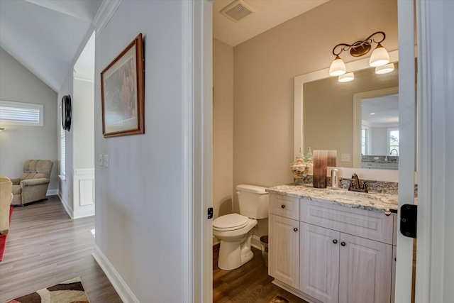 bathroom featuring toilet, wood finished floors, visible vents, vanity, and vaulted ceiling