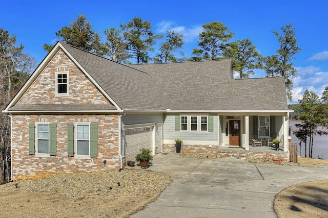 view of front facade with an attached garage, covered porch, driveway, and stone siding