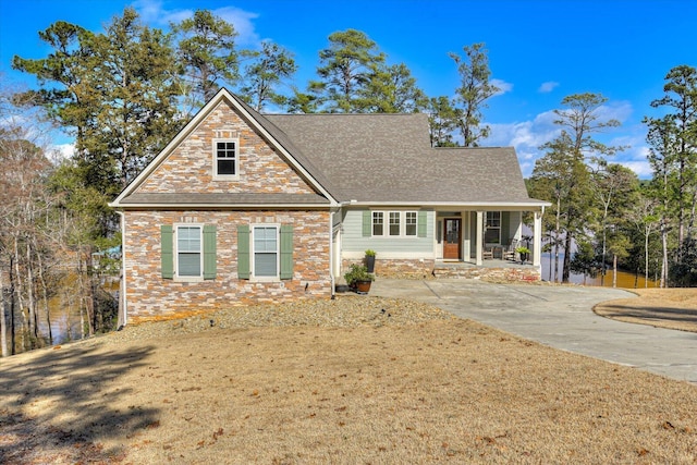 view of front facade with stone siding, a front lawn, and a porch