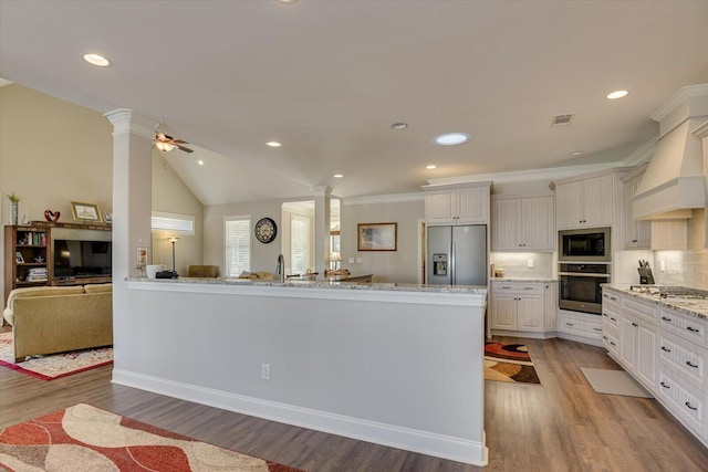 kitchen featuring visible vents, white cabinets, stainless steel appliances, ornate columns, and premium range hood