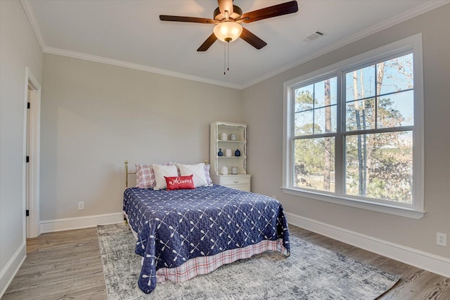 bedroom featuring baseboards, crown molding, visible vents, and wood finished floors