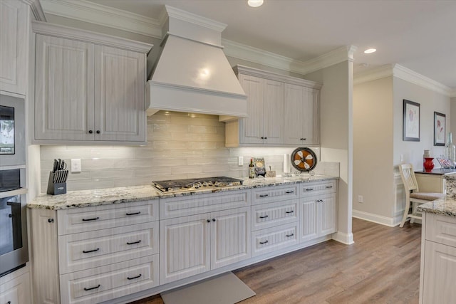 kitchen with stainless steel gas cooktop, custom exhaust hood, white cabinetry, and light wood-style floors