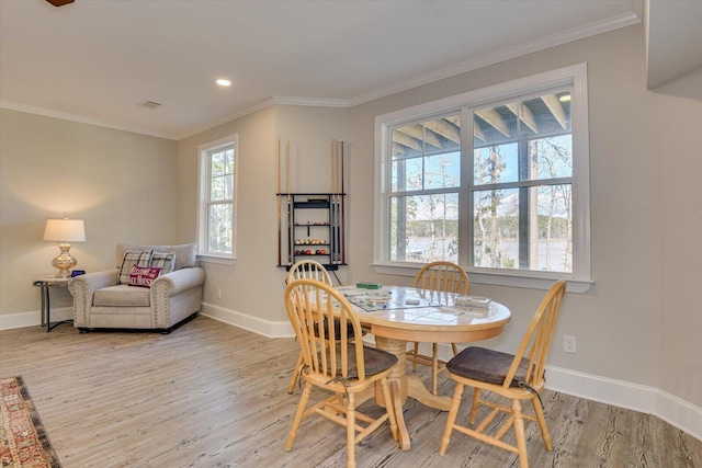 dining room with ornamental molding, light wood-type flooring, and baseboards