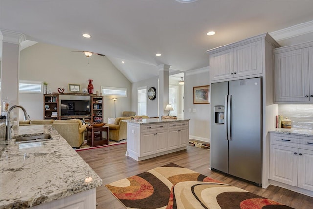 kitchen with open floor plan, a sink, white cabinetry, and stainless steel fridge with ice dispenser