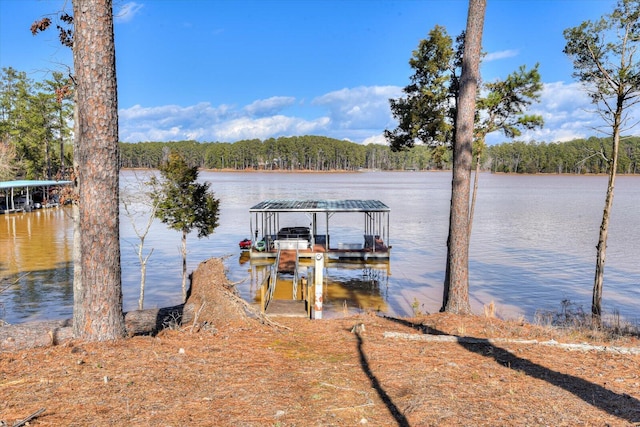 dock area with a water view, boat lift, and a forest view