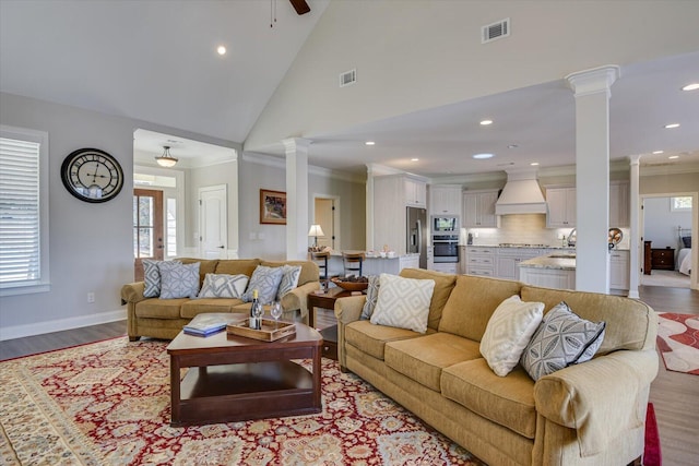 living area with ornamental molding, visible vents, decorative columns, and light wood finished floors