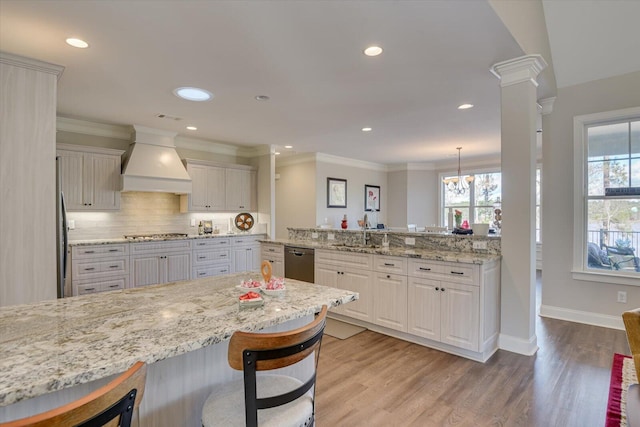 kitchen with a breakfast bar, stainless steel appliances, white cabinetry, premium range hood, and a peninsula