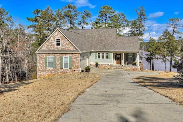 traditional home with a porch, a front yard, concrete driveway, and an attached garage