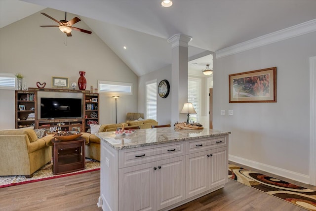 kitchen featuring light stone counters, white cabinetry, open floor plan, light wood-type flooring, and a center island