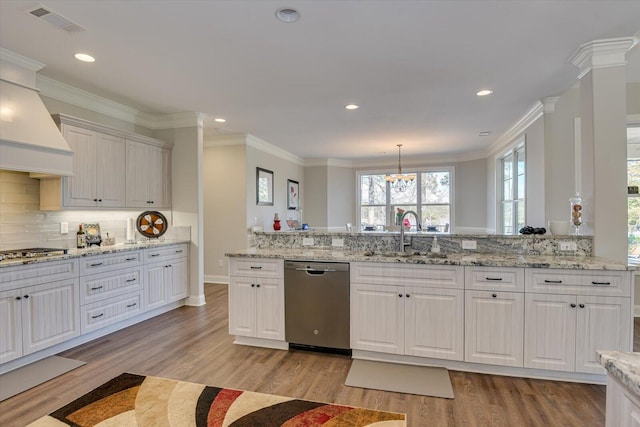 kitchen with decorative light fixtures, stainless steel appliances, custom range hood, white cabinetry, and a sink