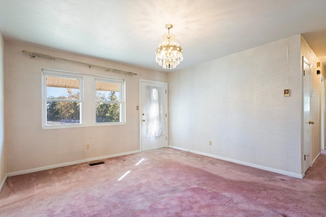 carpeted empty room with an inviting chandelier