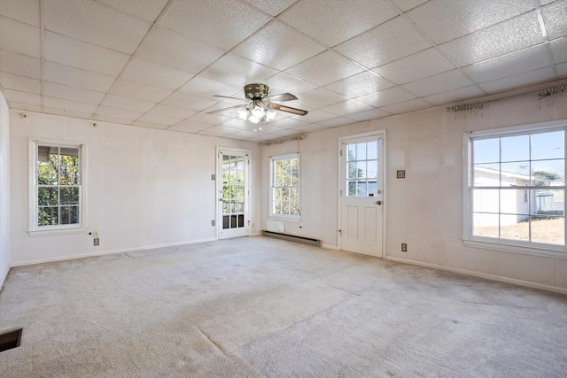 carpeted spare room with baseboard heating, a paneled ceiling, ceiling fan, and a wealth of natural light