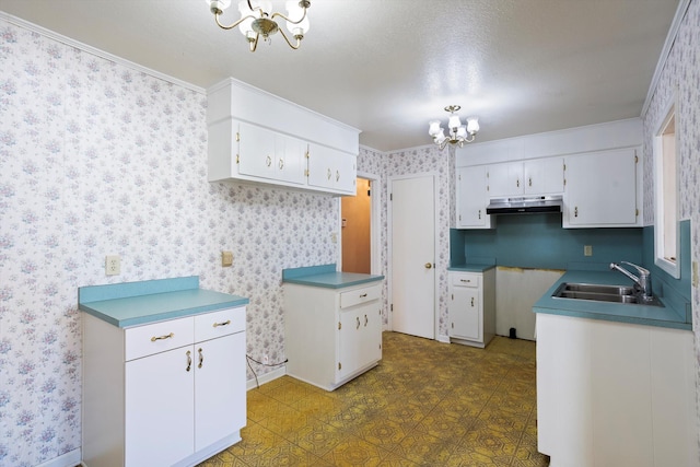 kitchen with crown molding, sink, white cabinets, and an inviting chandelier