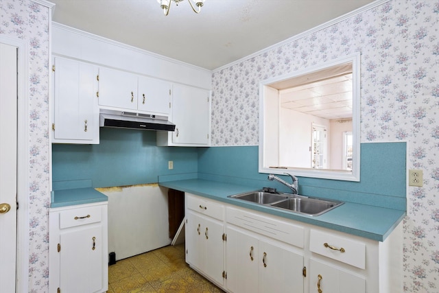 kitchen with white cabinets, crown molding, and sink