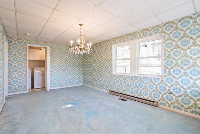 carpeted empty room with independent washer and dryer, a paneled ceiling, an inviting chandelier, and baseboard heating