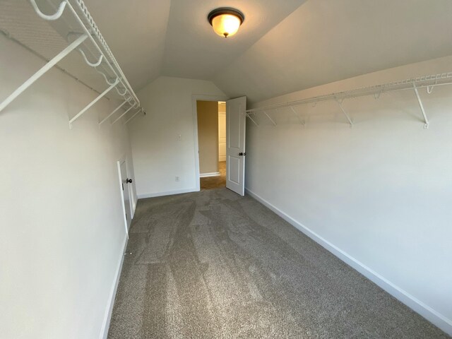 walk in closet with dark carpet and lofted ceiling