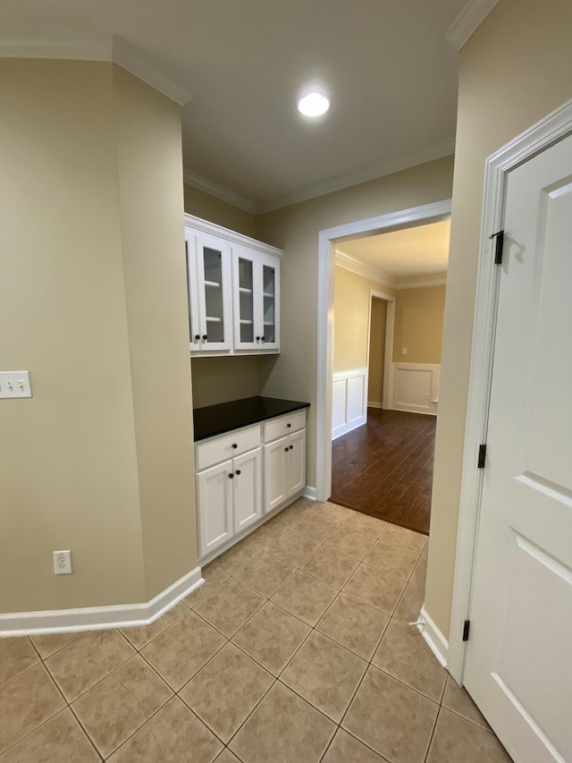 kitchen with white cabinets, light tile patterned flooring, and crown molding