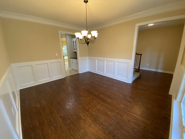 spare room with crown molding, dark wood-type flooring, and a chandelier