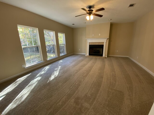 unfurnished living room with carpet flooring, a tile fireplace, and ceiling fan