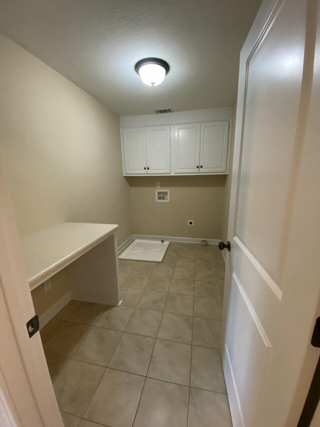 clothes washing area with hookup for a washing machine, light tile patterned floors, and cabinets