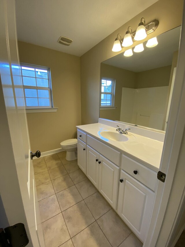 bathroom featuring tile patterned flooring, vanity, toilet, and walk in shower