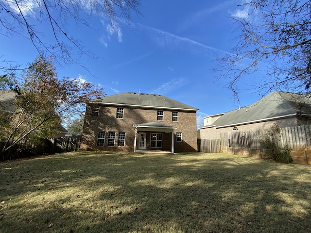 back of property with a yard and a patio