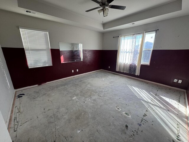 unfurnished room featuring a raised ceiling and ceiling fan