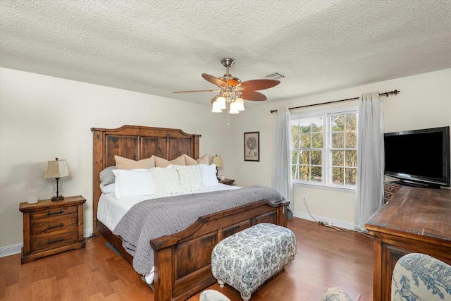 bedroom with wood-type flooring, a textured ceiling, and ceiling fan