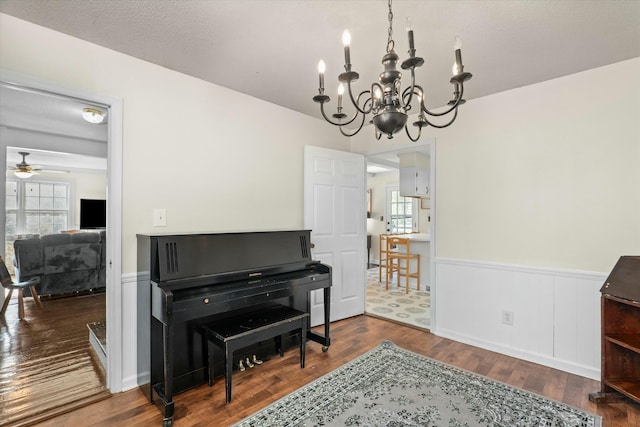 misc room featuring a textured ceiling, ceiling fan with notable chandelier, and dark wood-type flooring