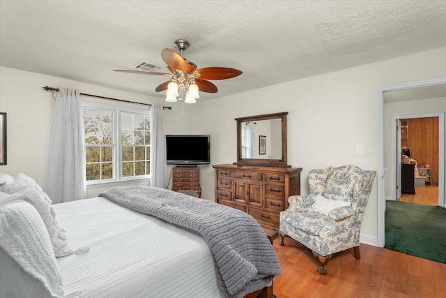 bedroom featuring ceiling fan, hardwood / wood-style floors, and a textured ceiling