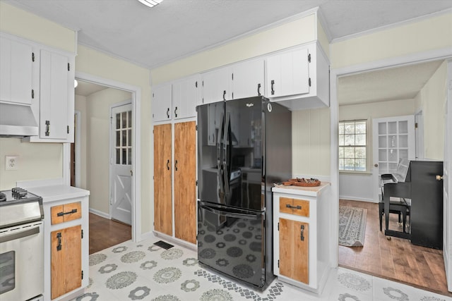 kitchen featuring electric range, white cabinets, black fridge, and premium range hood