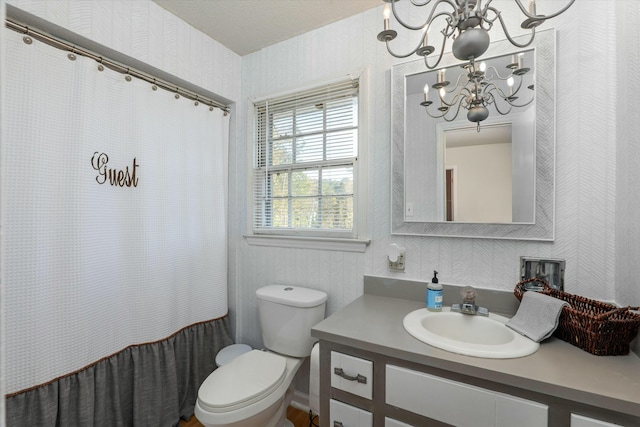 bathroom with a chandelier, vanity, and toilet