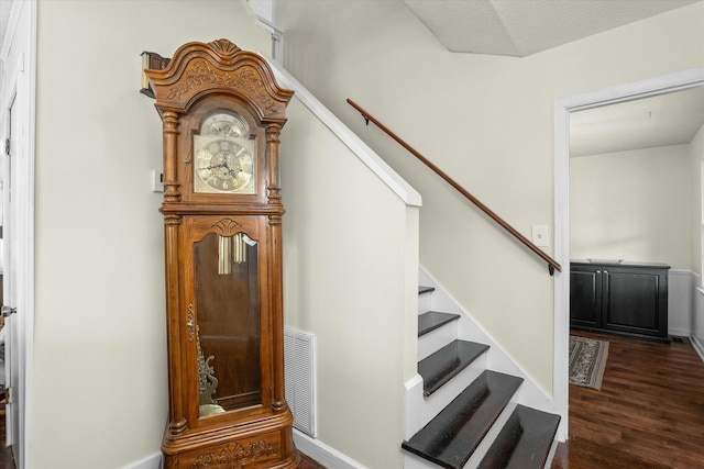 stairs featuring a textured ceiling and hardwood / wood-style flooring