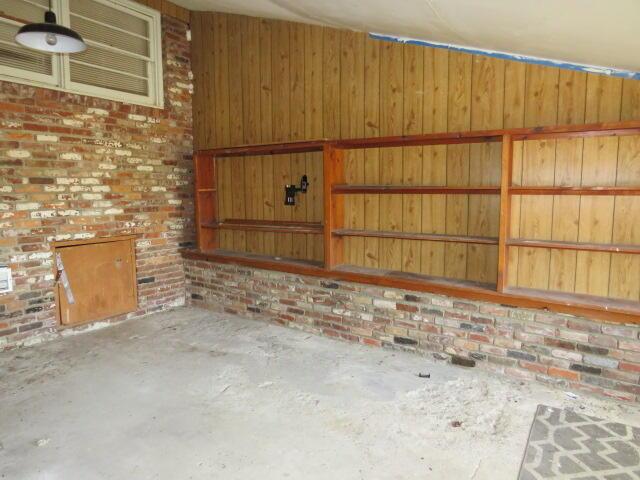 unfurnished living room with concrete flooring and brick wall