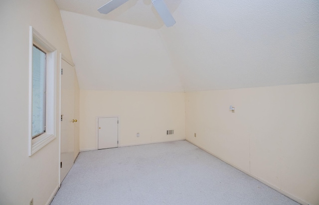 additional living space with a textured ceiling, ceiling fan, light colored carpet, and lofted ceiling