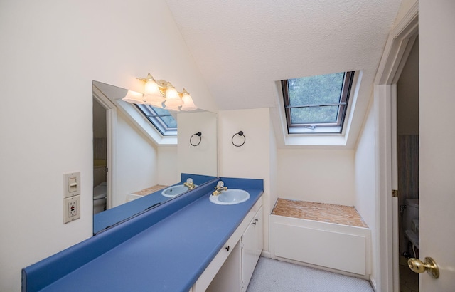 bathroom featuring vanity, a textured ceiling, a skylight, and toilet