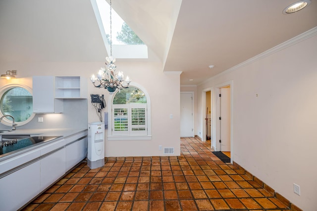 kitchen with white cabinetry, crown molding, a chandelier, and sink